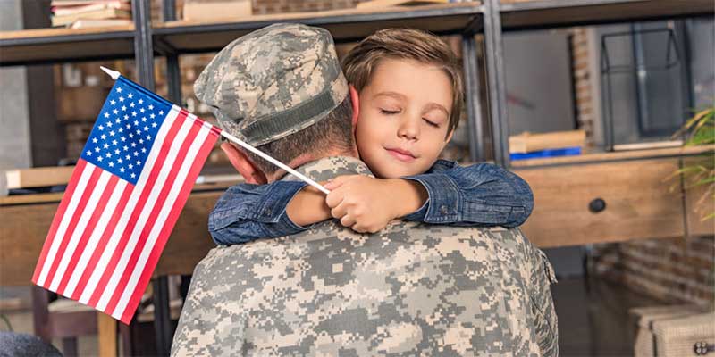 Military father and son with usa flag embracing